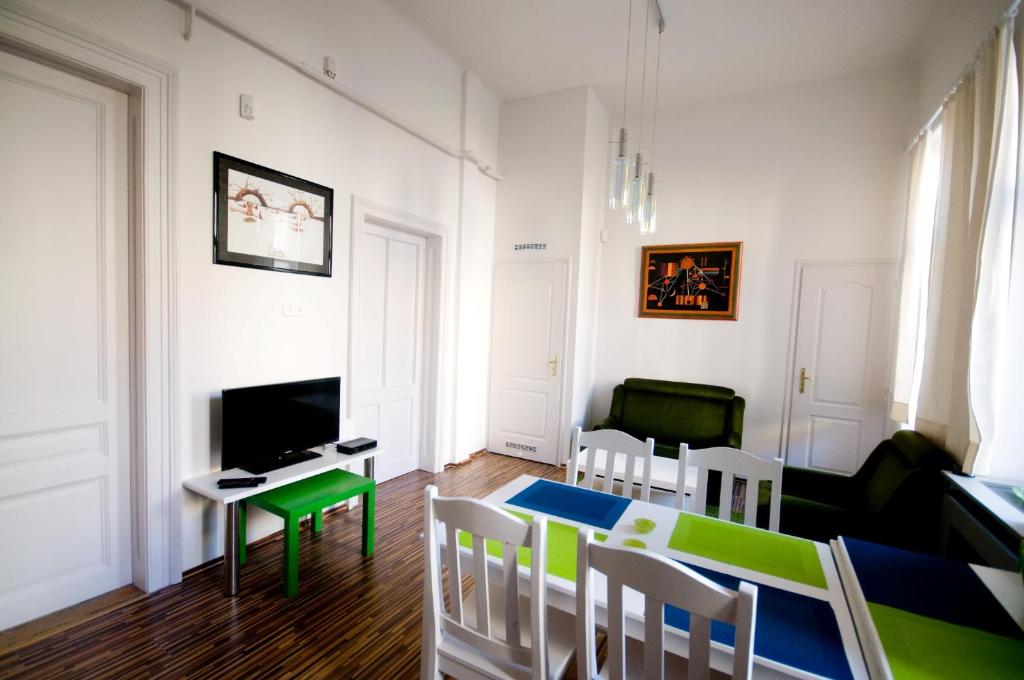 ein Wohnzimmer mit einem Tisch, Stühlen und einem TV in der Unterkunft CentrÁlom Apartman in Pécs