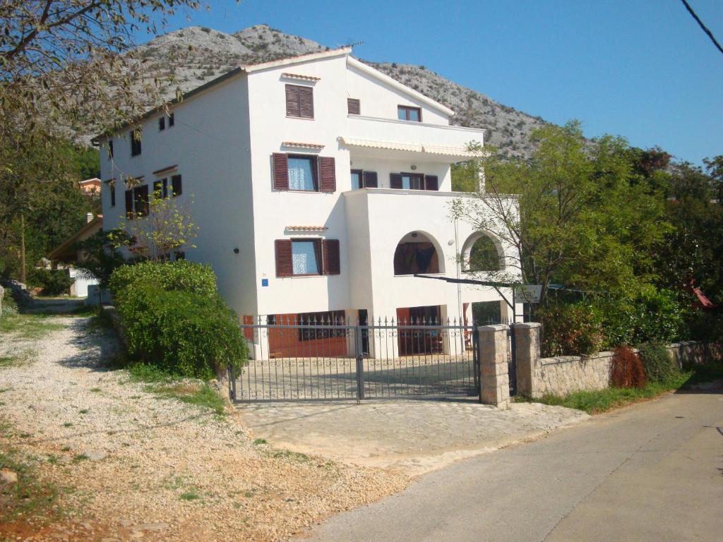 ein weißes Haus mit einem Zaun davor in der Unterkunft Apartments Vukelić in Starigrad-Paklenica
