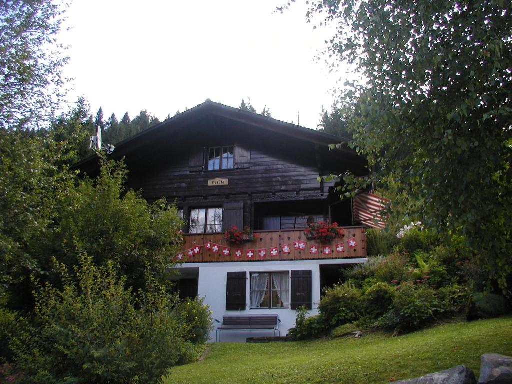a wooden house with flowers on the balcony at Ferienstudio Betula in Schwarzsee
