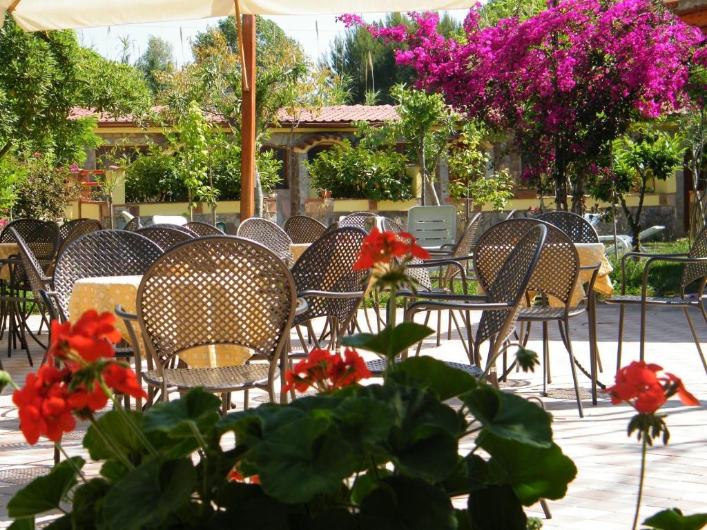 a group of chairs and tables with red flowers at Hotel Villaggio Tabù in Palinuro