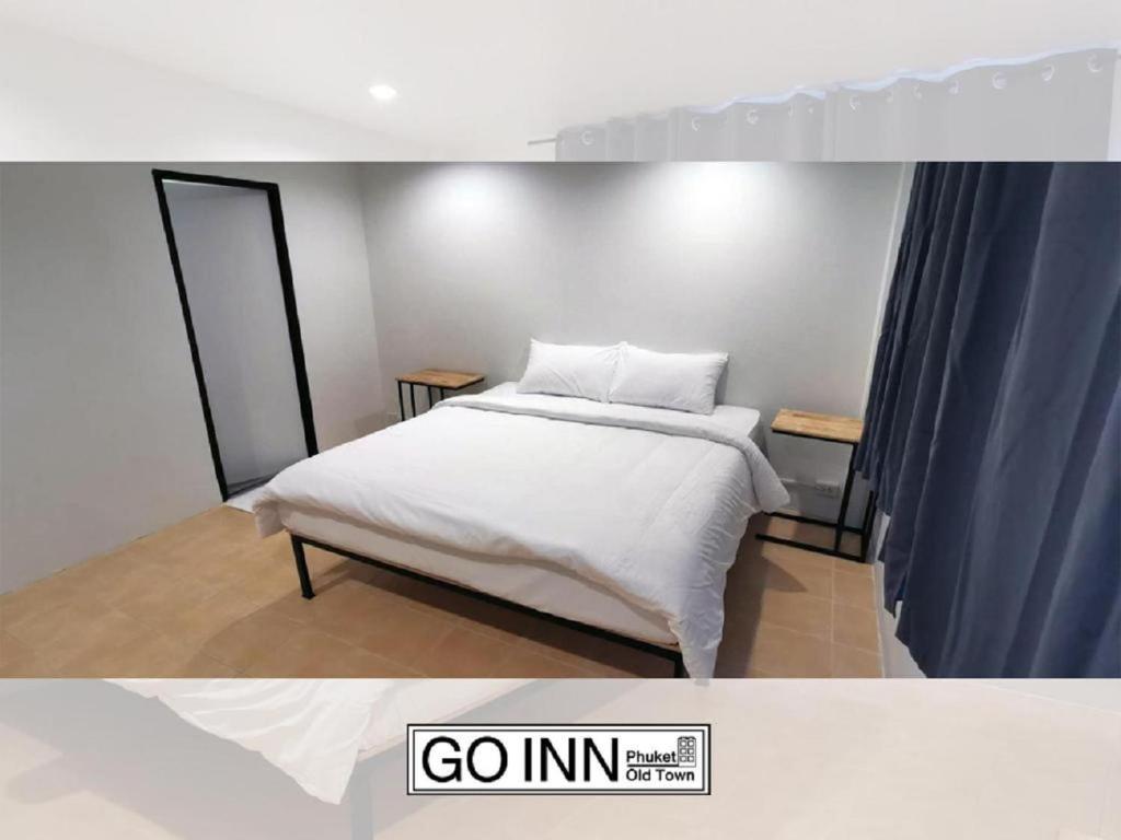 a bedroom with a white bed and a blue curtain at GO INN Phuket Old Town ภูเก็ตโอลทาวน์ ย่านเมืองเก่า in Phuket