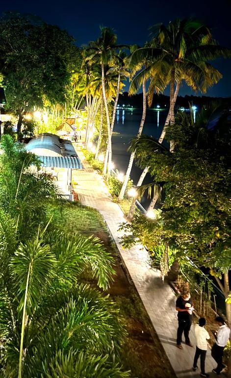a group of people walking down a sidewalk with palm trees at Jaladarshini Lakeside Gardens in Kollam