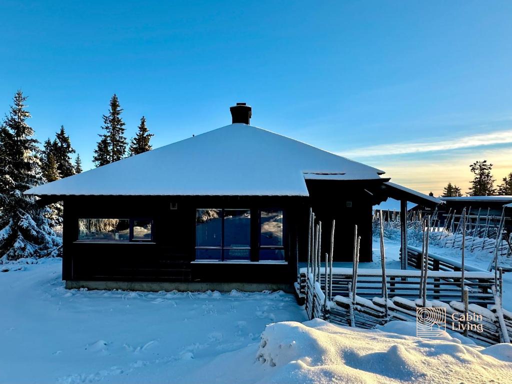 a cabin with a snow covered roof in the snow at Cabin at Sjusjøen Birkebeiner trail ski in out, 8 beds, 2 bathrooms & Wifi in Sjusjøen