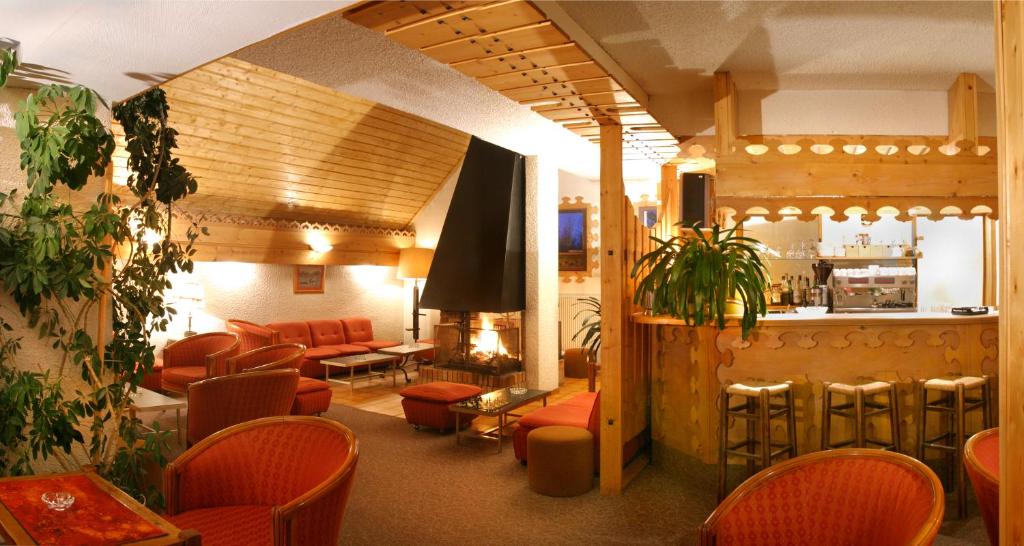 a waiting room with red chairs and a bar at Hotel Adret in Les Deux Alpes