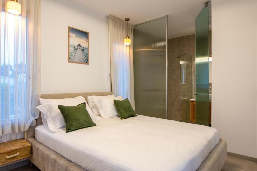 a bedroom with a large white bed with green pillows at Secondfloor- Luxurious Modern Suite in the Golan Heights in Qasrîne