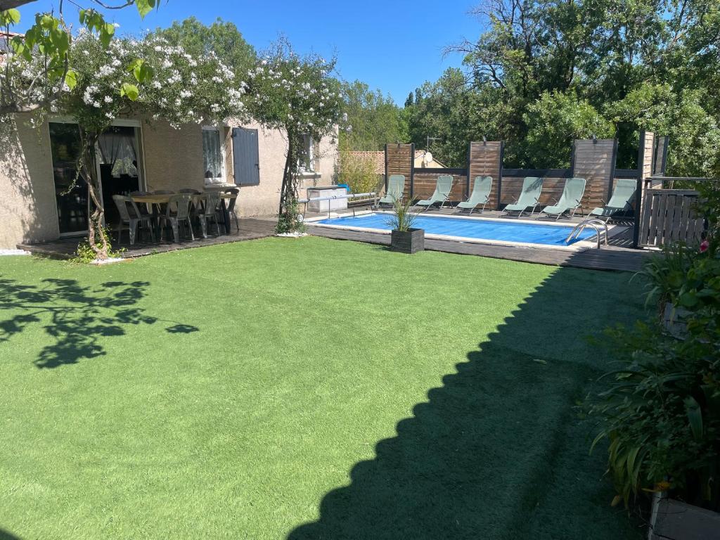 einen Garten mit einem Pool mit Stühlen und einem Tisch in der Unterkunft Villa 200m2, 3 suites, patio avec salle jeux, 1 piscine CHAUFFE DE DEBUT AVRIL A FIN OCTOBRE in Maruéjols