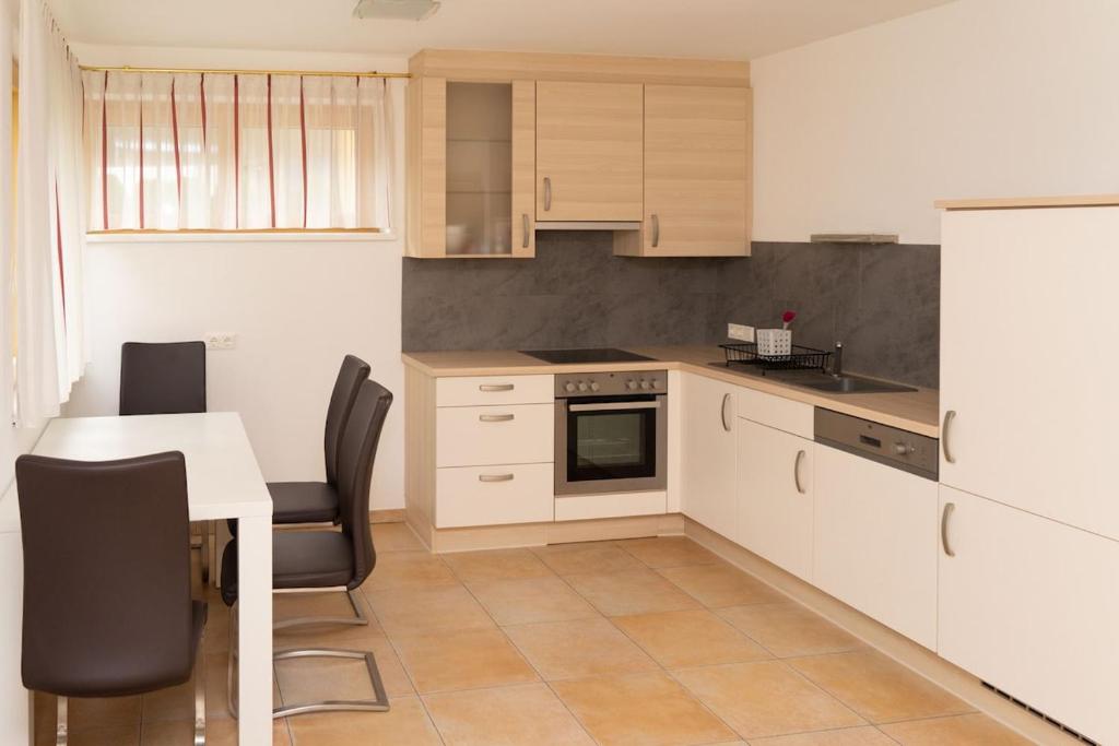 a kitchen with white cabinets and a table and a refrigerator at Cozy Garconniere near Innsbruck in Völs