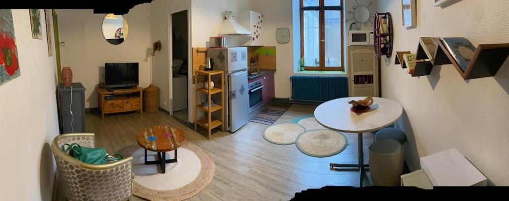 un salon avec une table et une cuisine dans l'établissement Charmant meublé deux chambres, à Châteauroux