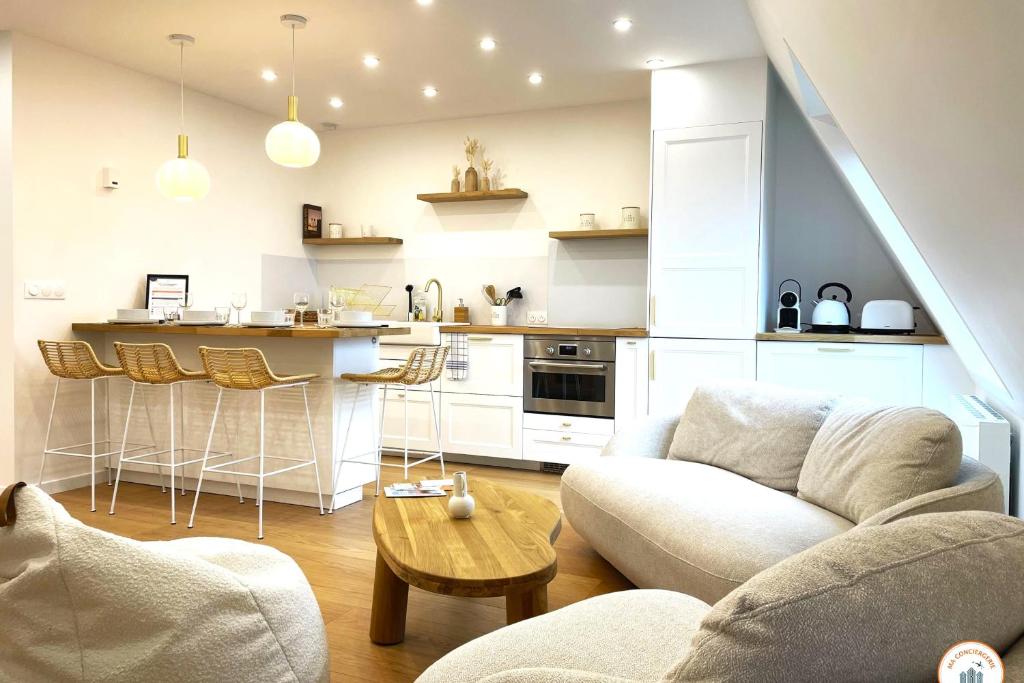 un salon avec un canapé et une cuisine dans l'établissement Le Petit Palais - 50m Plage - Vue mer et campagne, à Tourgéville