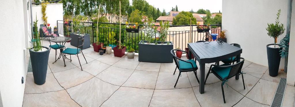 un patio avec une table, des chaises et des plantes en pot dans l'établissement Appartement Brignoles en secteur calme, à Brignoles