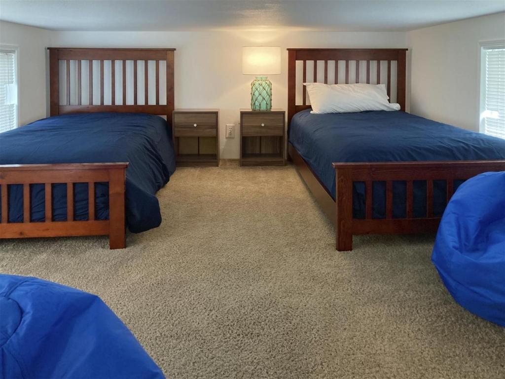 a bedroom with two beds with blue sheets and a lamp at Boat House in Fort Bragg