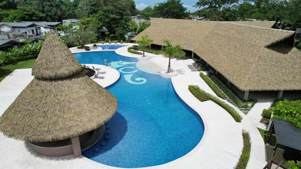 an overhead view of a resort swimming pool with a straw umbrella at Casa Cardumen - Ciudad Del Mar, in Jaco in Jacó