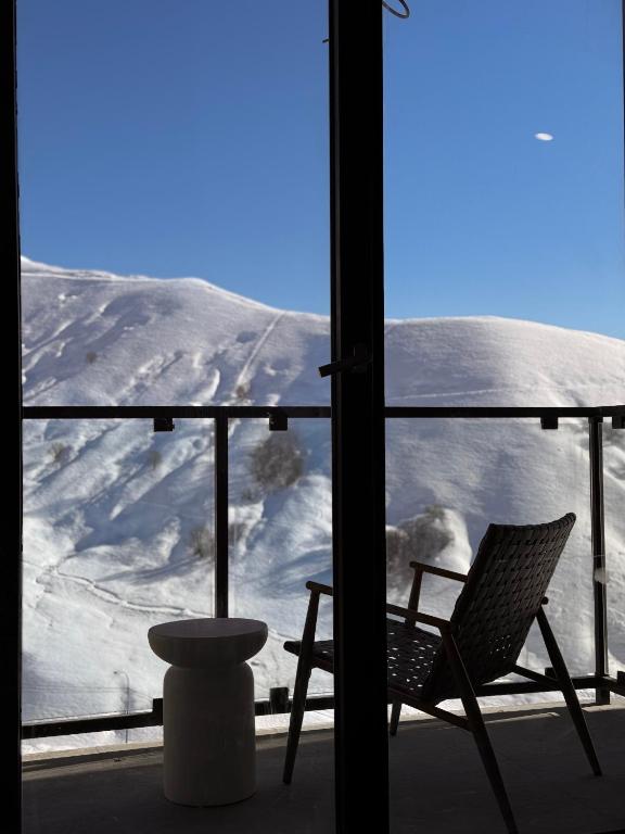 a chair on a balcony with a snow covered mountain at Luxury duplex with mountain views, new gudauri in Gudauri