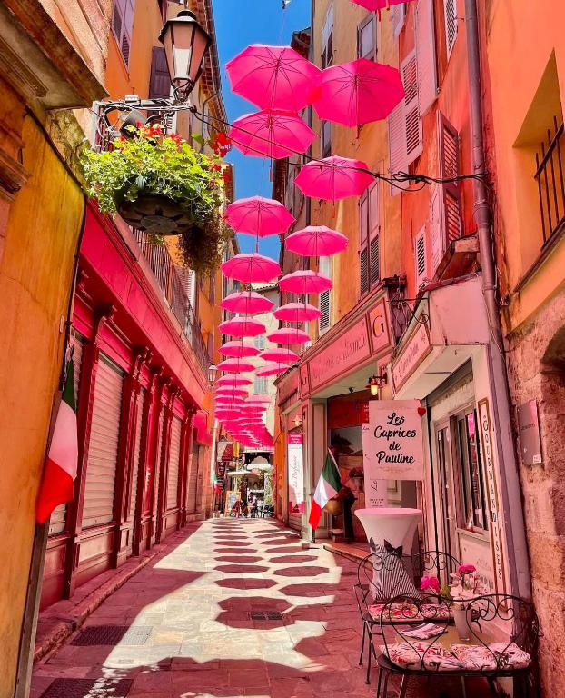 une rangée de parasols roses suspendus au-dessus d'une rue dans l'établissement Le cozy grasse, à Grasse