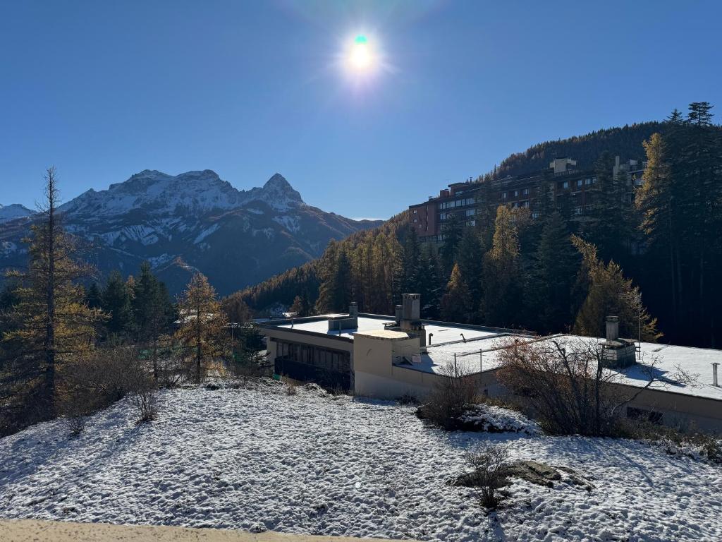 un bâtiment sur une colline enneigée avec des montagnes en arrière-plan dans l'établissement T3 Praloup proche des Tennis, à Uvernet