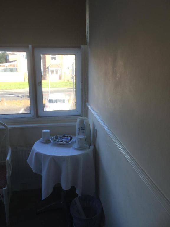 a table in a room with two windows at Colnbrook Lodge Guest House in Slough