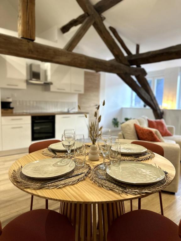 une table en bois avec des assiettes et des verres à vin dessus dans l'établissement Bali à Charleville-Mézières - Hypercentre à quelques pas de la Place Ducale - 4 personnes, à Charleville-Mézières