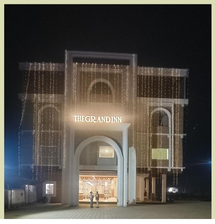 a large building with a sign that reads their grand entry at The Grand Inn Resort in Dum Duma