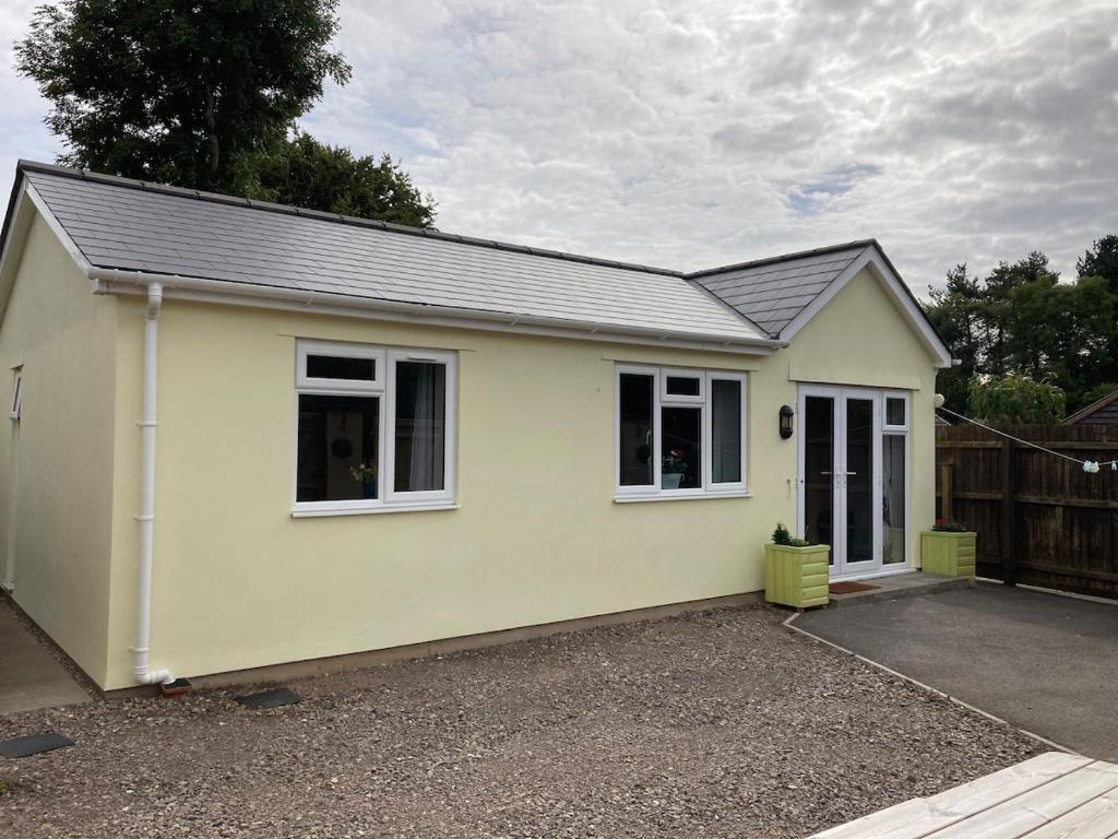a yellow house with white windows on a driveway at Ty Bach Melyn, car parking and private courtyard in Bridgend