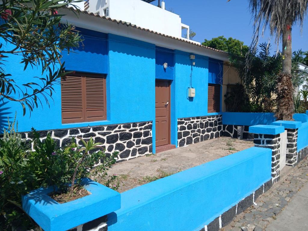 ein blaues Haus mit einer blauen Bank davor in der Unterkunft Mille Nuits Appartement in Tarrafal