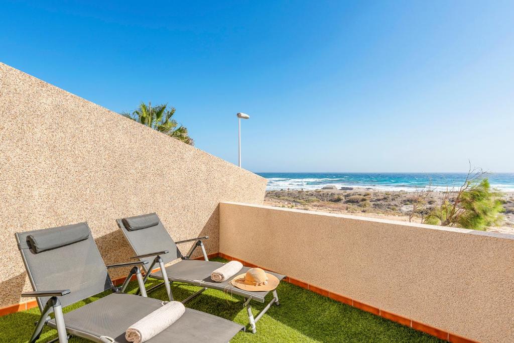 2 sillas y una mesa en un balcón con vistas a la playa en MEDANO4YOU Sunrise Medano, en El Médano