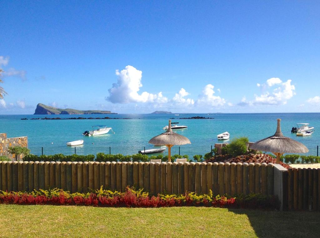 a fence with umbrellas and a view of the ocean at Coral Villa in Cap Malheureux