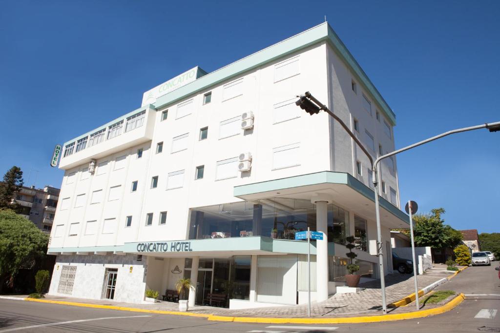 a white building on the corner of a street at Hotel Concatto in Farroupilha