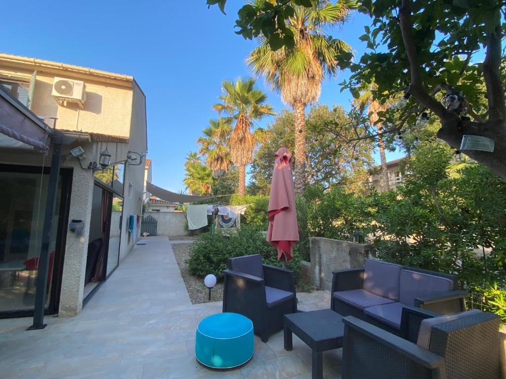 d'une terrasse avec des chaises, un parasol et des palmiers. dans l'établissement Maison bord de mer en Corse, à Borgo