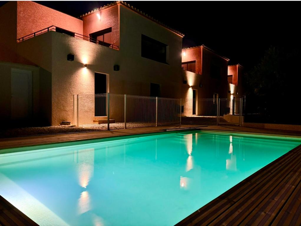 une piscine devant une maison la nuit dans l'établissement VillaPalmaé1, à Lapalme