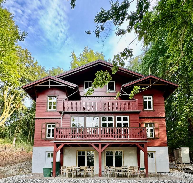 a red house with a balcony and tables and chairs at Haus Elim für Gruppen und Großfamilien in Heringsdorf