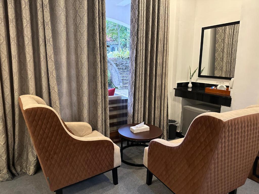 a room with two chairs and a table and a mirror at Elegant Hotel in Kandy