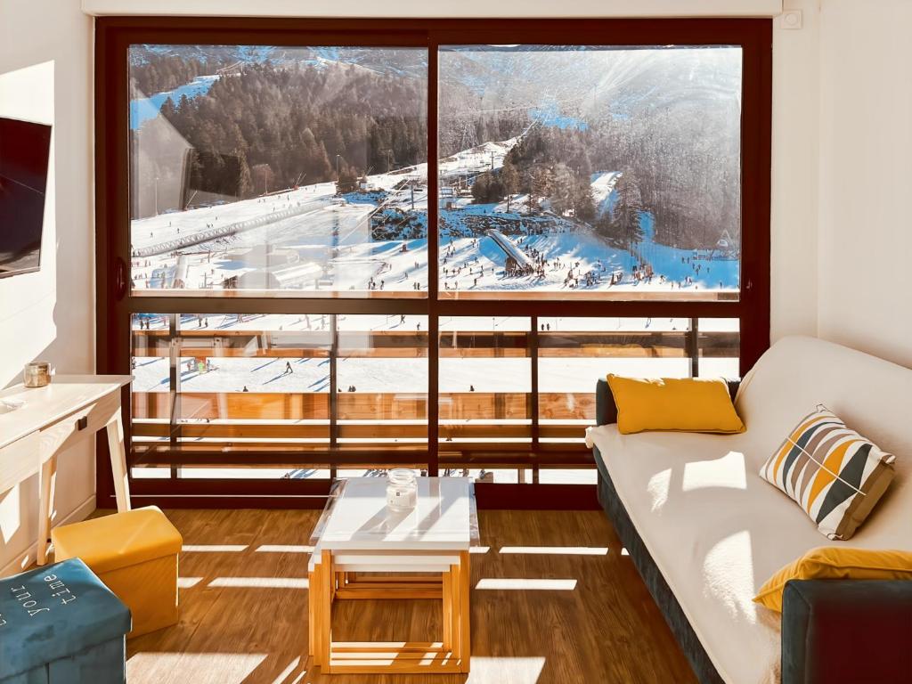 ein Zimmer mit einem Sofa und einem großen Fenster in der Unterkunft Le Haut Griou aux pieds sur les pistes, 8pers, cœur station, Le Lioran in Laveissière
