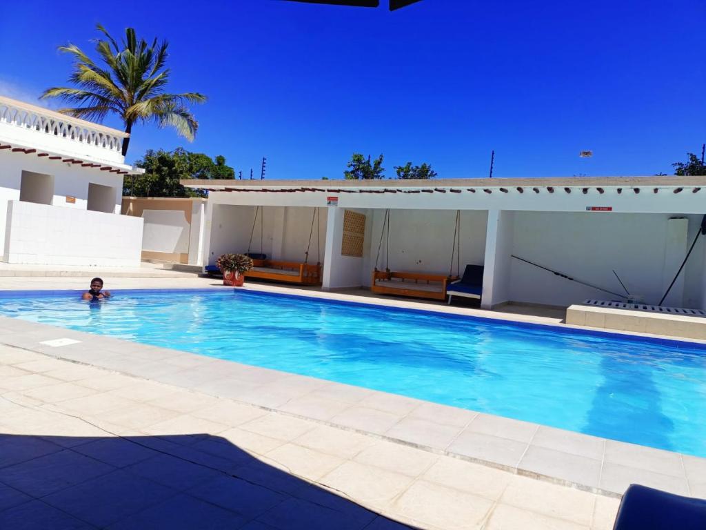 a person in a swimming pool next to a house at Becky Homes Diani Beach- 4BR with AC and Swimming Pool in Diani Beach