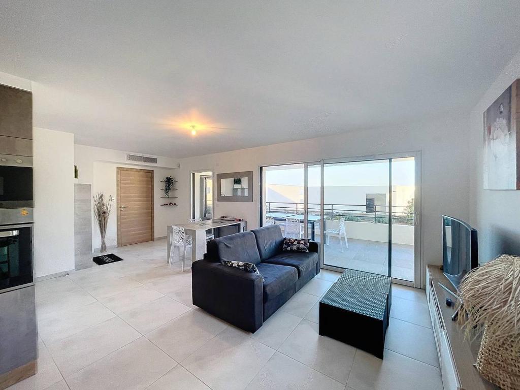 un salon avec un canapé et une télévision et une cuisine dans l'établissement Charmant T3 dans une résidence neuve avec piscine, à Calvi