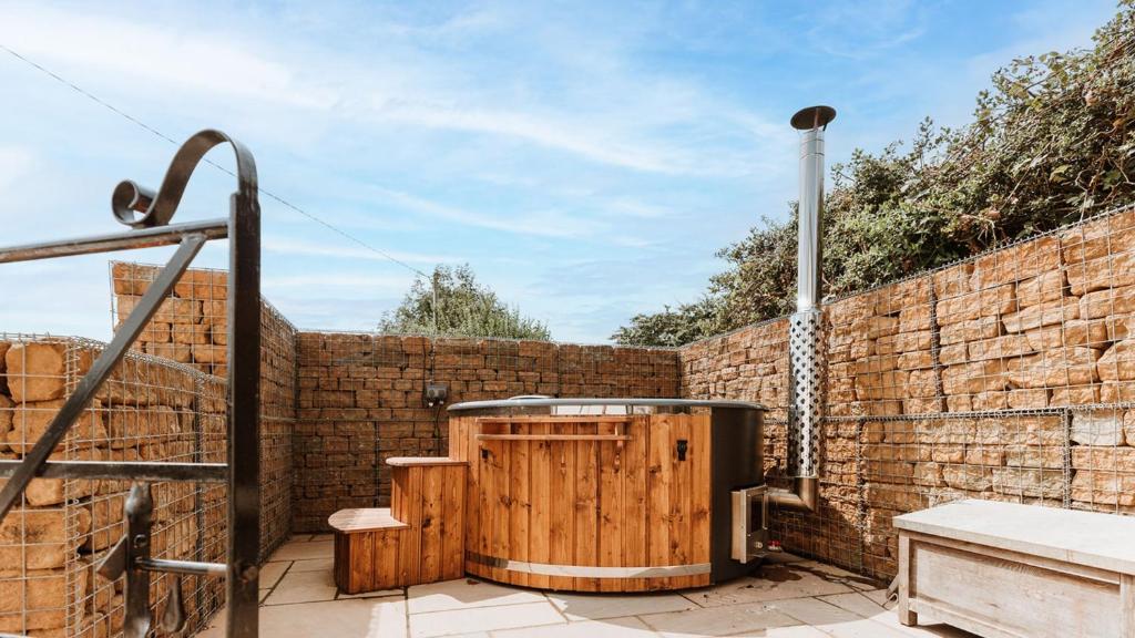 a brick wall with a hot tub next to a fence at The Piggery in Yarpole