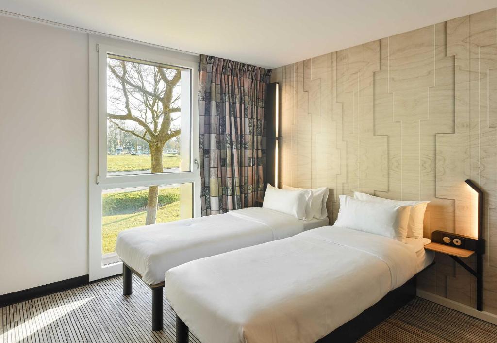Dos camas en una habitación con ventana. en B&B HOTEL Marne-la-Vallée Val d'Europe, en Serris