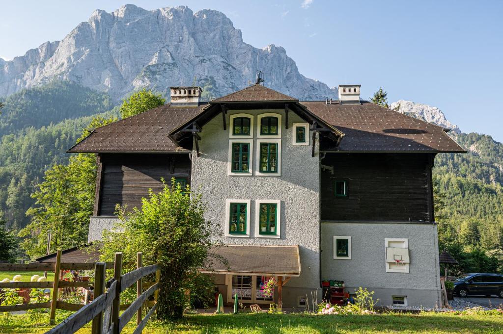una grande casa con una montagna sullo sfondo di Nationalpark Gesäuse Lodge a Gstatterboden