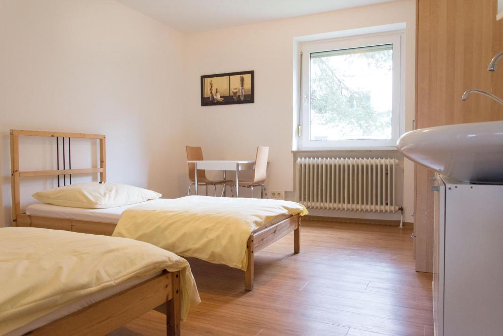 a room with two beds and a sink and a window at 1, 2, sleep Hostel Nürnberg Messe in Nuremberg