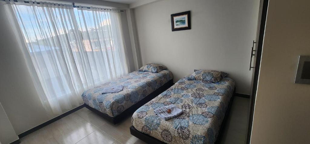 a room with two beds and a large window at Molina House Sandona in Sandoná