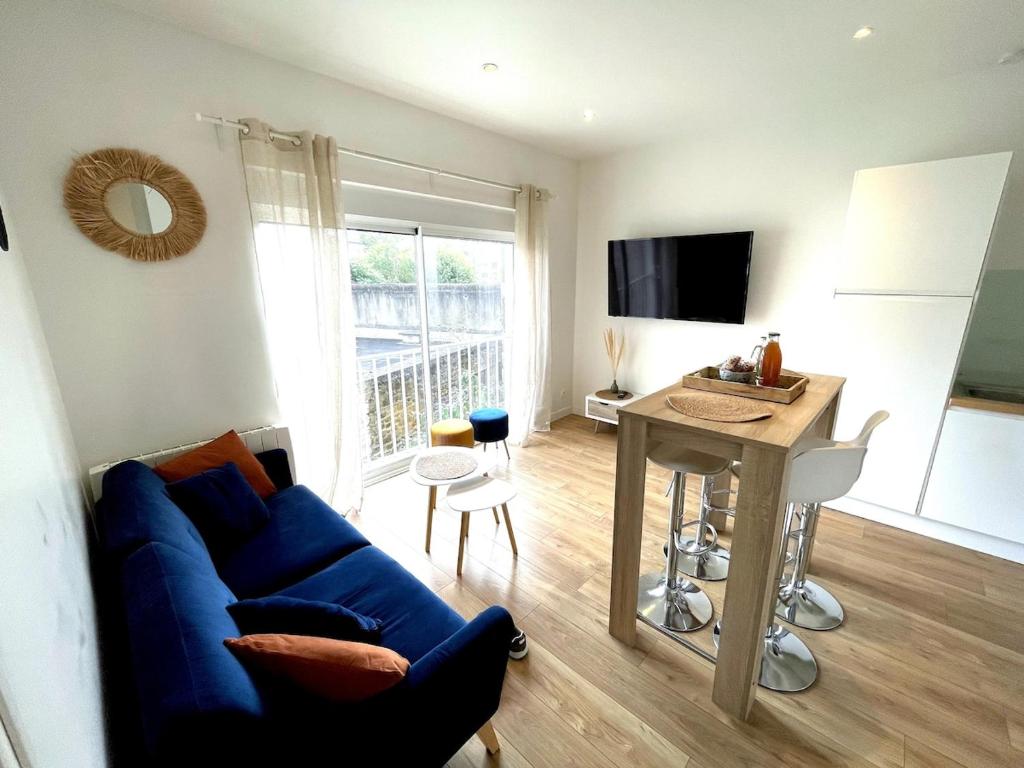 un salon avec un canapé bleu et une table dans l'établissement Le Clemenceau - centre ville, proche gare et commerces, à Saint-Brieuc