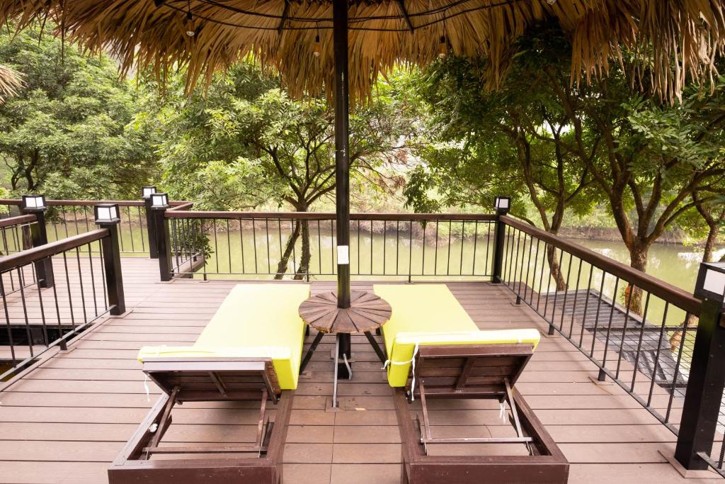 a deck with two benches and an umbrella at Trang An Ecolodge in Ninh Binh