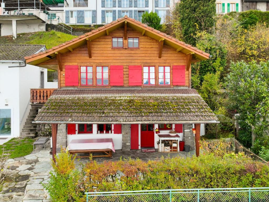 una casa roja con un banco delante en Chalet Le Cabanon by Interhome, en Saint-Gingolph