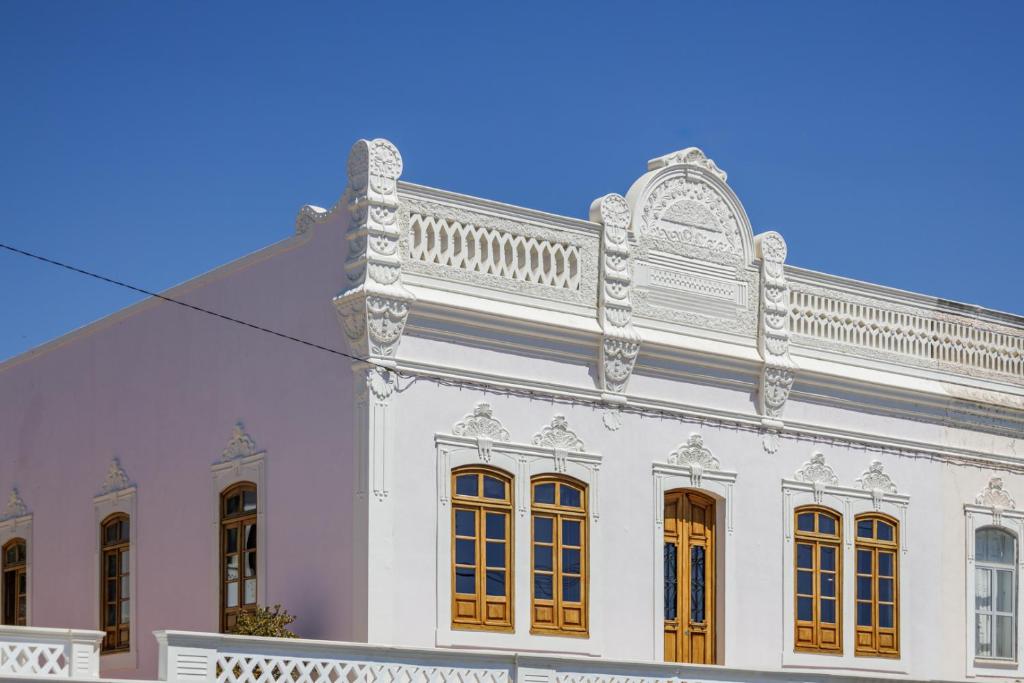 un edificio bianco con porte arancioni e balcone di Casa de Marim AL a Olhão