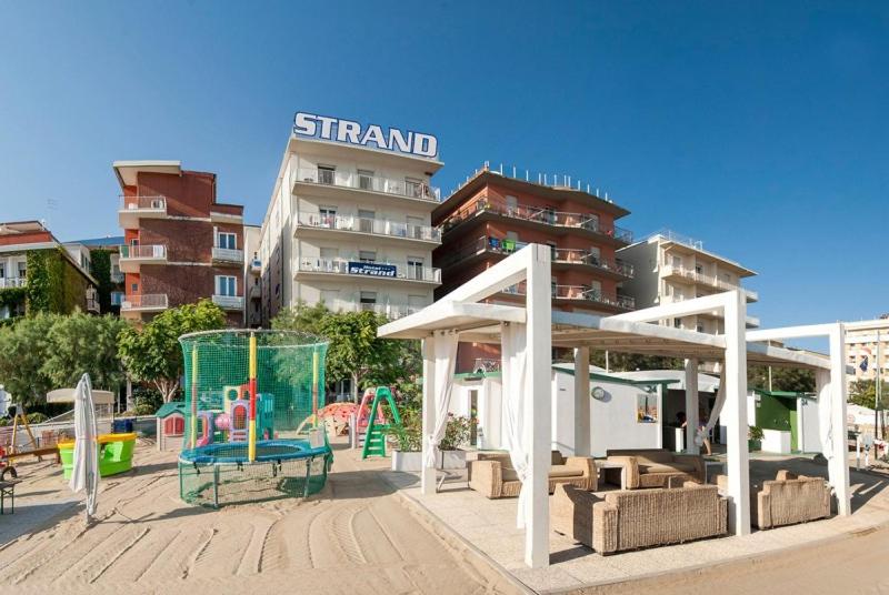a playground in front of a tall building at Strand Hotel in Gabicce Mare
