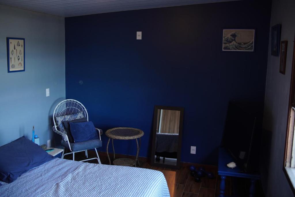 1 dormitorio con una pared azul, 1 cama y 2 sillas en Cabana Solitude - Concha, en Florianópolis