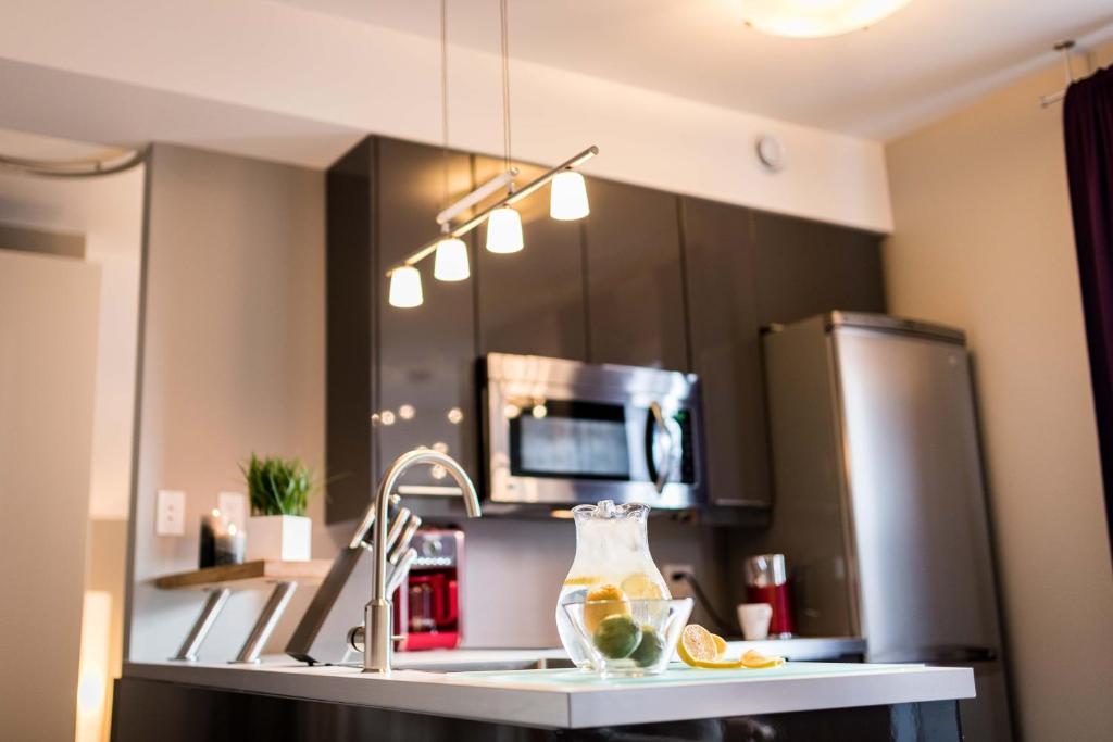a kitchen with a sink and a refrigerator at Château Queen by Bower Hotels & Suites in Moncton
