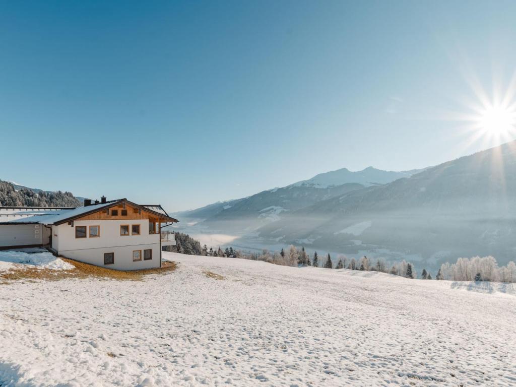 a house on a snowy hill with the sun in the background at Apartment Talmoosen-Bauer by Interhome in Dorf