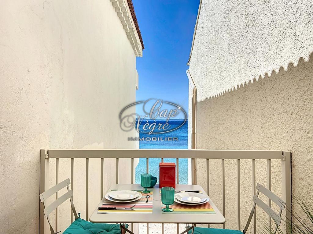 une table avec des assiettes et des verres sur un balcon dans l'établissement Studio 2 personnes vue mer résidence pieds dans l'eau à Cavalière, au Lavandou