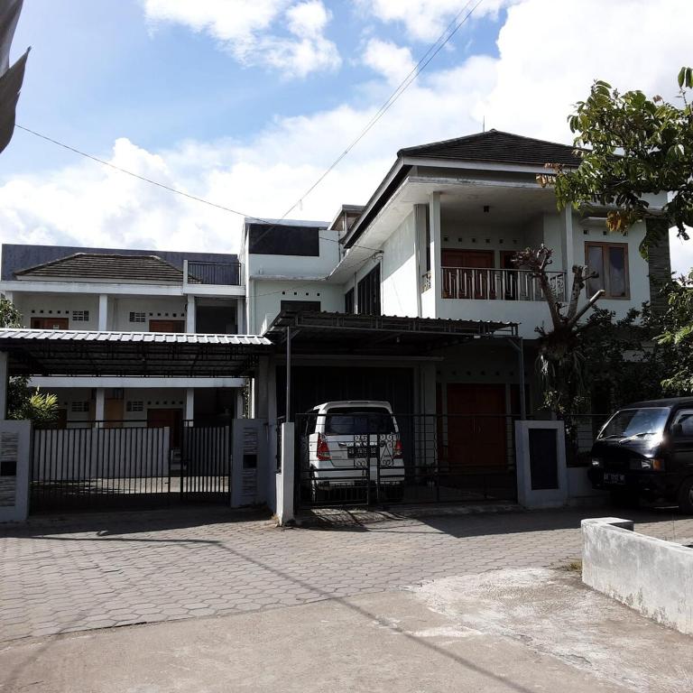 a white house with a car parked in front of it at Kadipiro Homestay in Ngabean