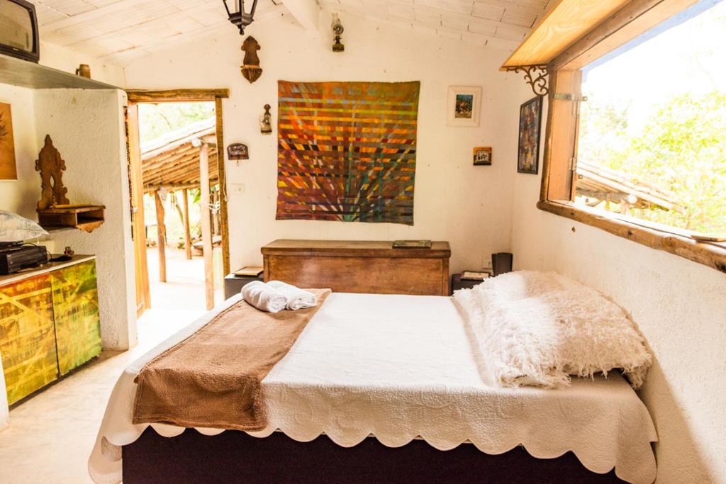 een slaapkamer met een bed en een schilderij aan de muur bij Hospedagem Morro dos Muricis in Piuí